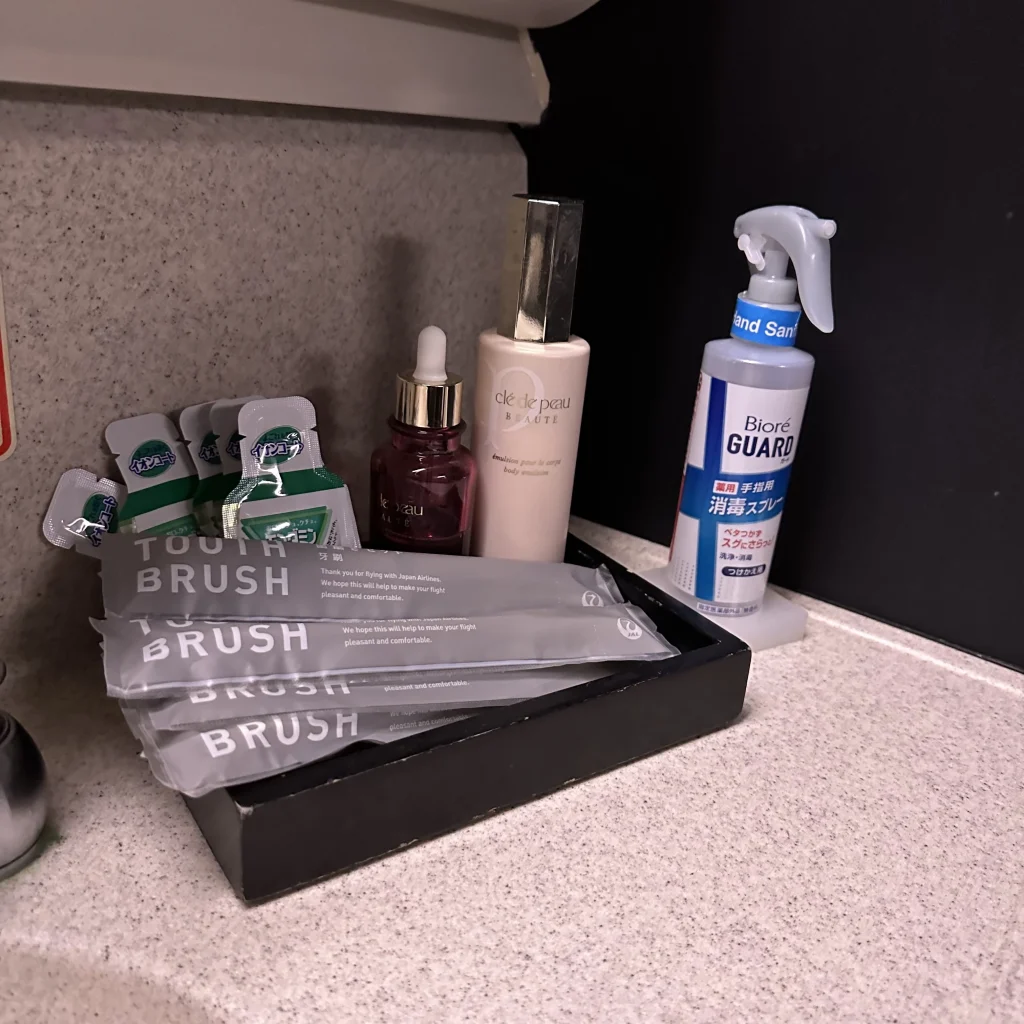 Japan Airlines first class bathroom features toothbrushes, lotions, and mouthwash