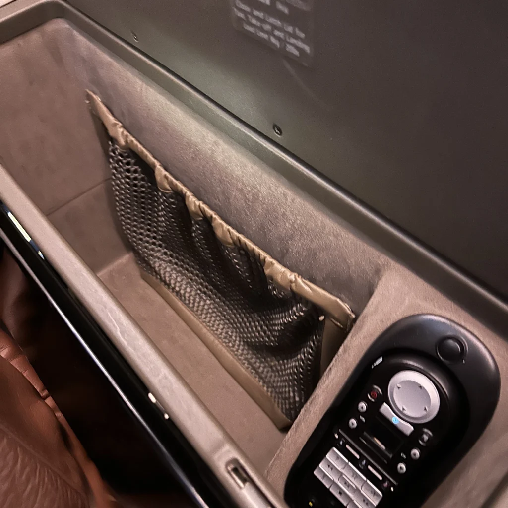Japan Airlines first class has a large storage compartment and in flight phone next to the seat
