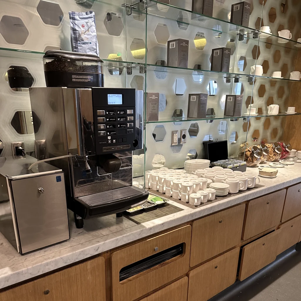 There is a coffee machine, snacks, and candy near the entrance of the Qantas First Class Lounge LAX