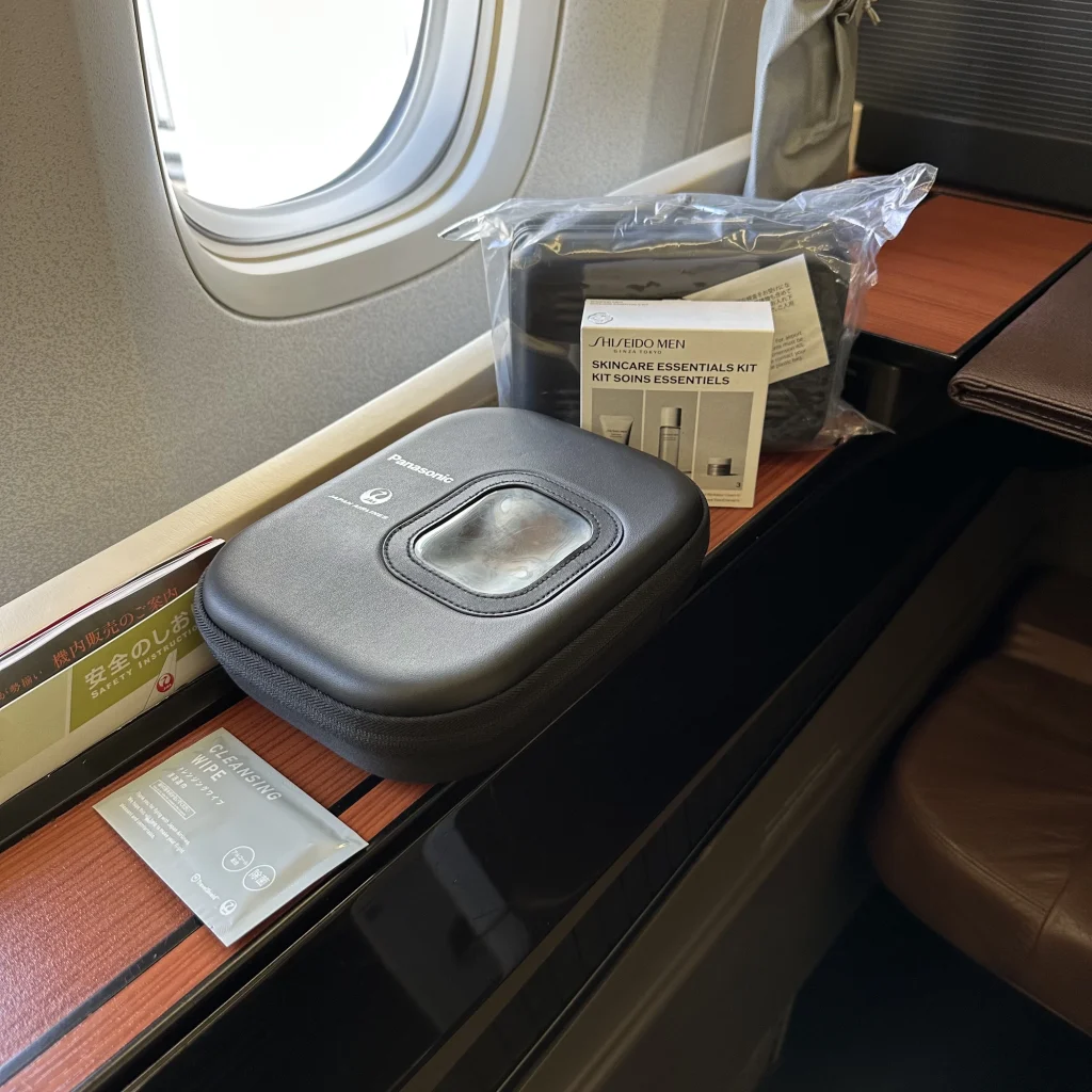 When you board Japan Airlines first class, you have noise canceling headphones, cleaning wipe, slippers, and amenity kit waiting for you at your seat