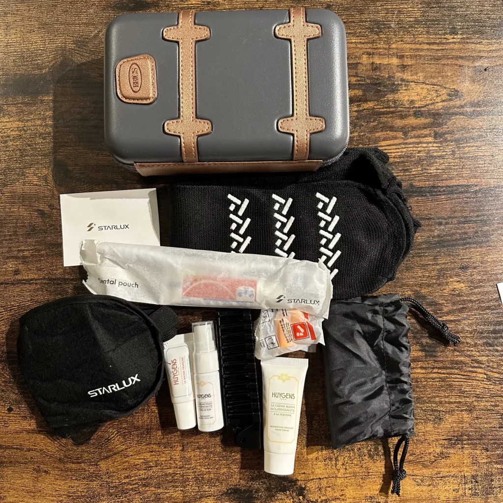 Starlux business class from Los Angeles to Taipei has an amenity kit with socks, an eye mask, a foldable comb, earplugs, a Starlux sticker, a toothbrush and toothpaste, and a mini pouch containing a facial spray, lip balm, and moisturizing cream